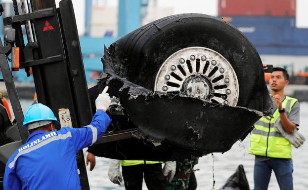 Unos trabajadores levantan una rueda del avión siniestrado en Yakarta, Indonesia.