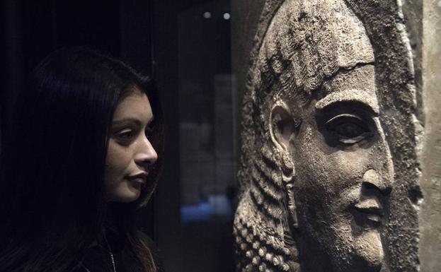 Una trabajadora del museo posa frente a un relieve con el rostro del rey asirio Asurbanipal. 