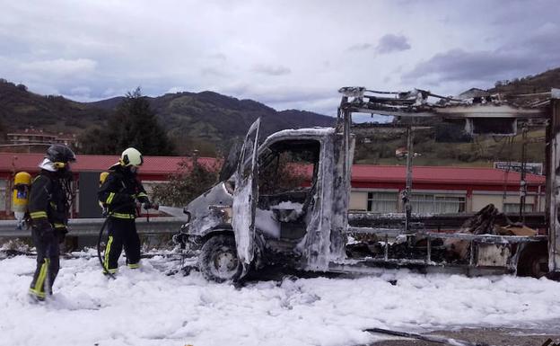 Los bomberos trabajando en la extinción del fuego, que calcinó por completo la furgoneta.