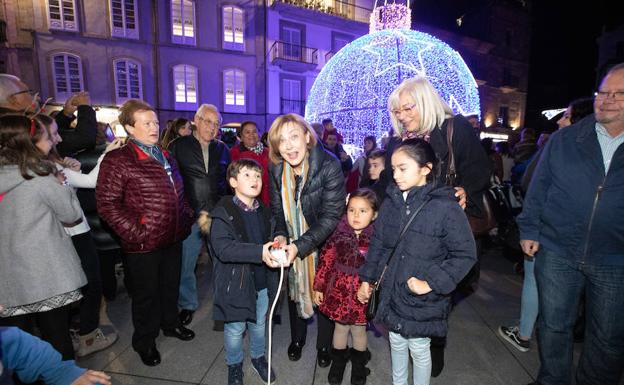 Un grupo de niños enciende el botón de las luces junto a la alcaldesa y a la concejala de Festejos. 