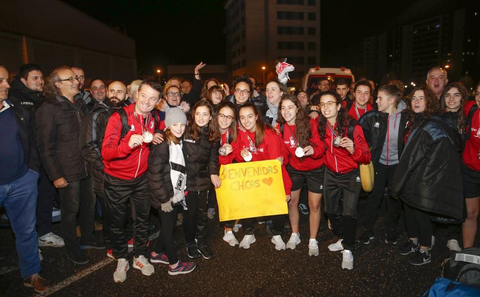 Las jugadoras y cuerpo técnico del Telecable, acompañadas por familiares y amigos, tras su llegada a Gijón. 