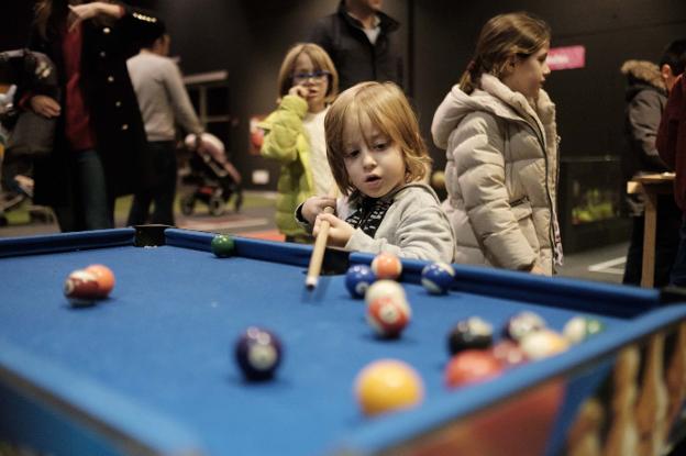 Un niño practica con el billar en Mercaplana. 