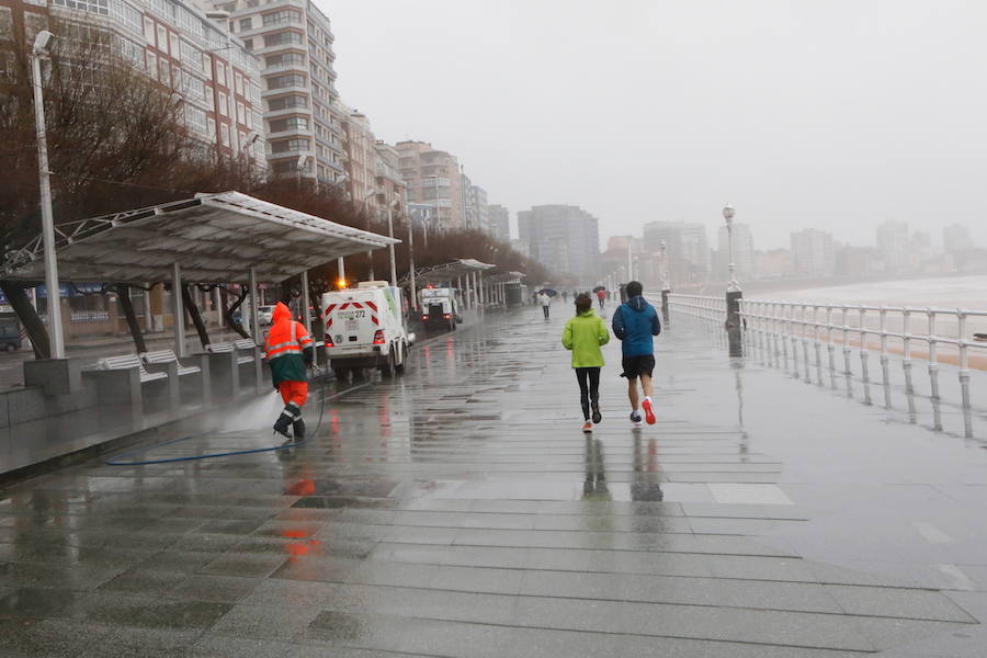 El paseo gijonés del Muro ha amanecido con algunas de sus escaleras cerradas debido a los daños causados por el temporal de lluvia y viento. Operarios de Emulsa han procedido a la limpieza de la arena depositada en el paseo tras la pleamar.