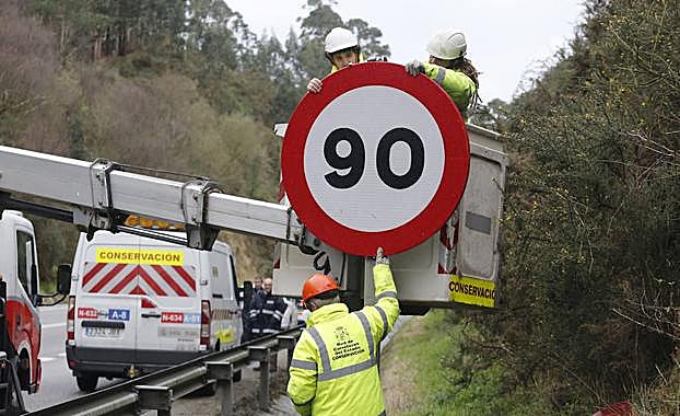 Operarios, colocando una señal de limitación a 90 km/h