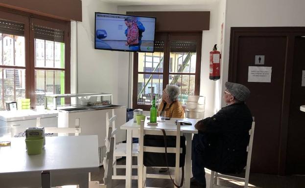 Vecinos del pueblo de Javier Ardines ven las noticias en la televisión del bar. 