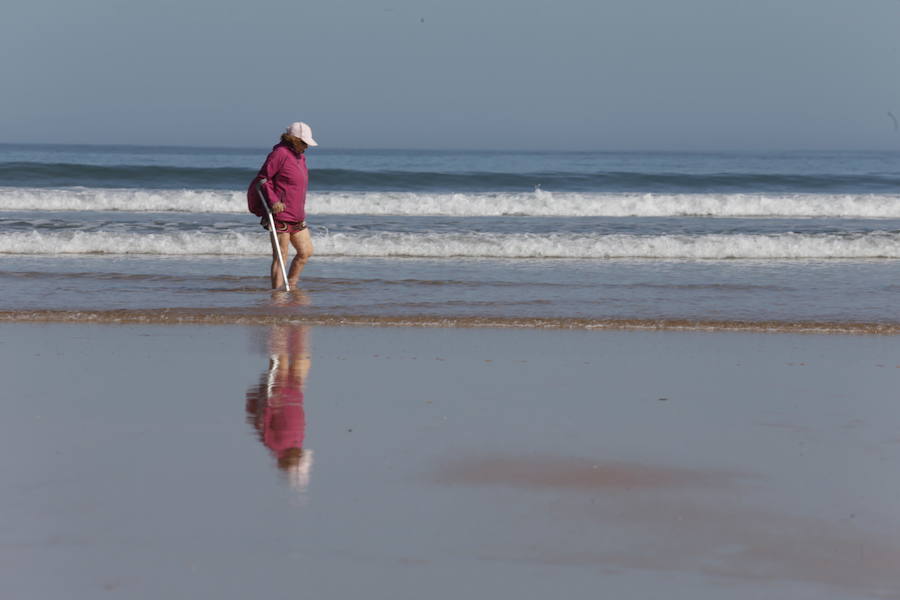 Decenas de personas se animaron a pasear por la Playa de San Lorenzo, bajo el sol y por la gran extensión de arena que dejó la bajamar