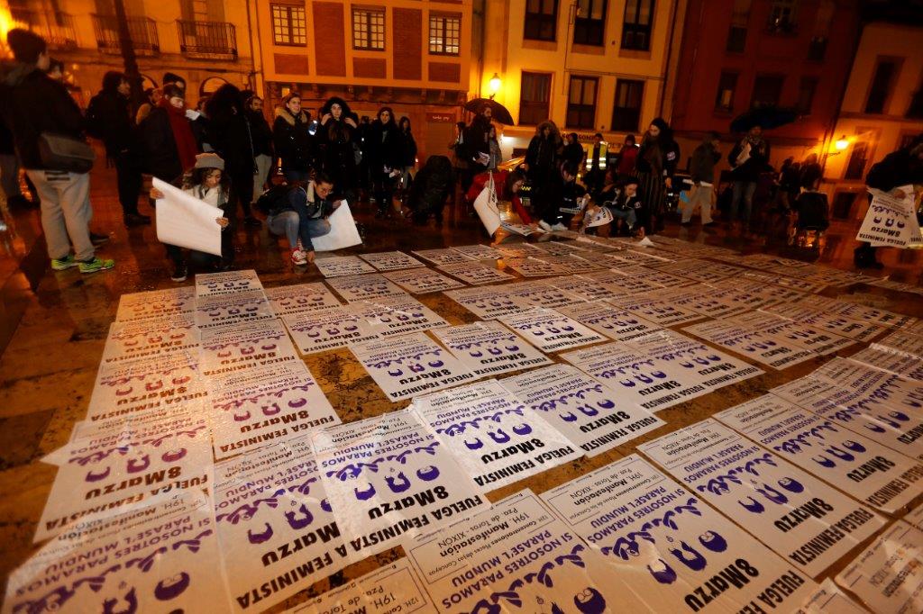 Un veintena de personas comenzó la jornada de huelga general feminista con una pega de carteles convocando a la manifestación de esta tarde en Gijón