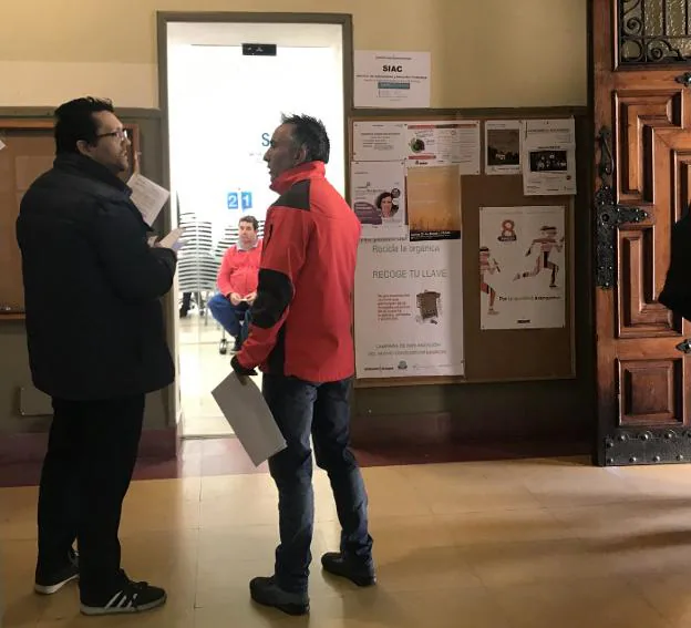 Dos hombres esperan para entregar la documentación. 