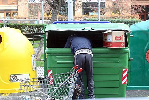 Un hombre rebusca en un contenedor de basura de Laviada. 
