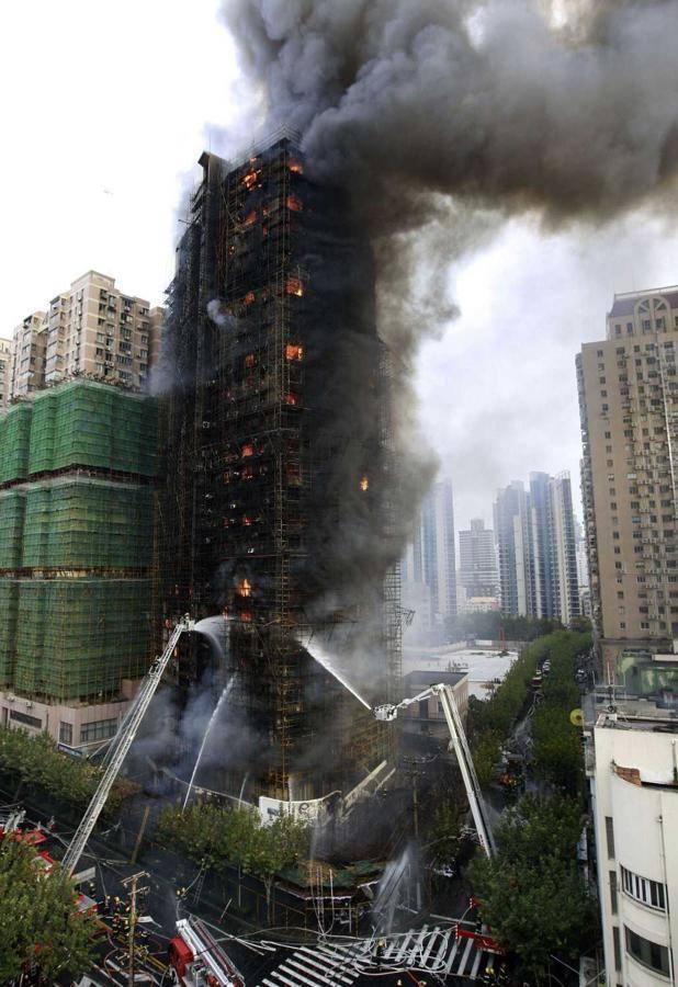 Bomberos sofocando el incendio en una torre residencial en Shanghái, China el 15 de noviembre de 2010