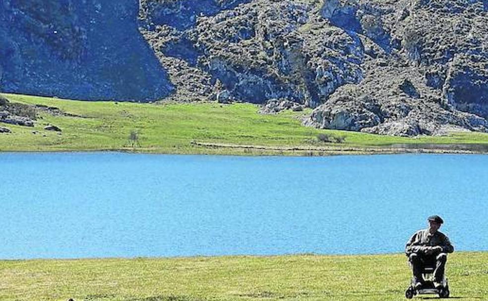 Un turista, con su silla de ruedas, a orillas del lago Ercina. 