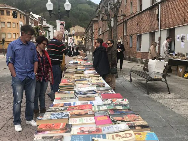 Varias personas observan los libros de segunda mano ubicados en las calles de Blimea. 