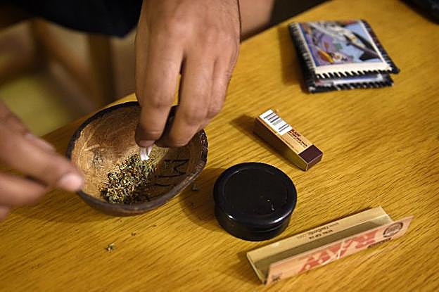 Un joven se prepara un porro en una sociedad cannábica. 