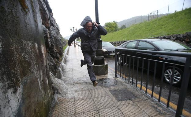 Un hombre pega un salto para esquivar el agua que arrolla por la pared tras la trombas de agua.