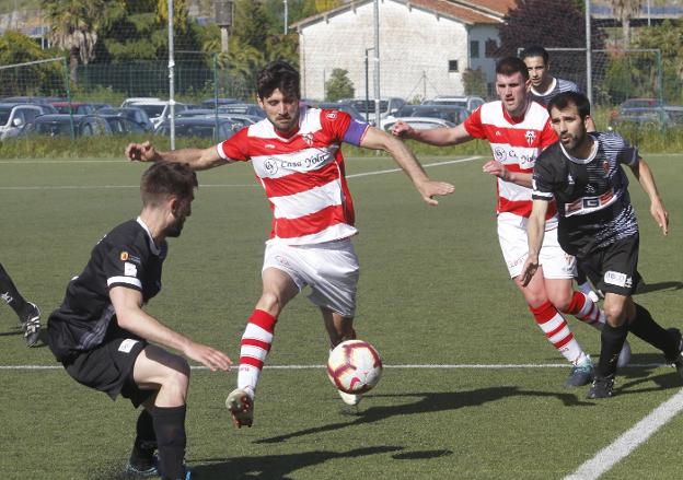 Marcos Ramos, del Racing de la Guía, con su compañero Arroyabe atrás, ante un jugador del Luarca, en el partido disputado ayer en el campo de Braña-Sur. 