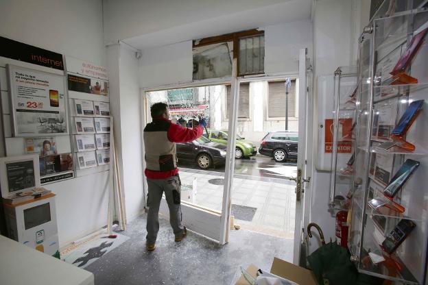 Un operario retira el escaparate destrozado por los cacos. 