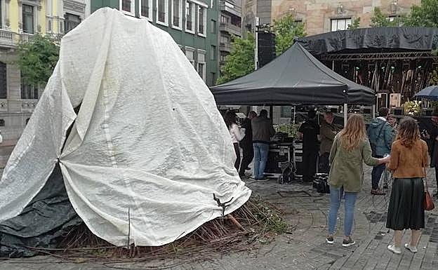 La hoguera de la plaza Porlier de Oviedo, cubierta por plásticos frente a la lluvia.