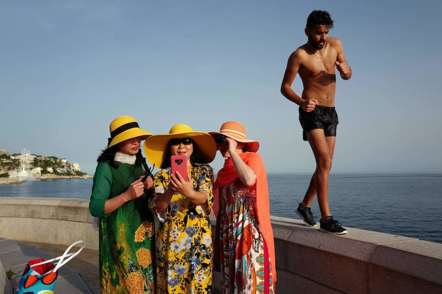 Un hombre pasa junto a un grupo de turistas que se protegen contra el sol en la ciudad de la Riviera francesa de Niza.