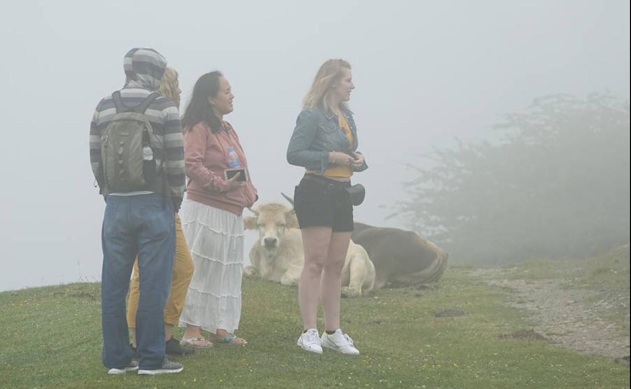 Un grupo de turistas, este domingo, en los Lagos de Covadonga cubiertos por la niebla. 