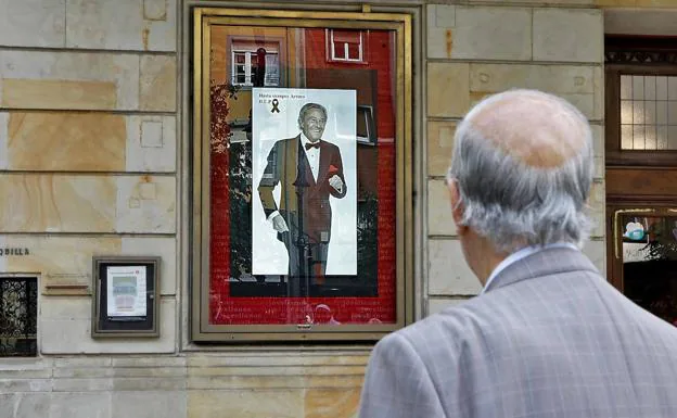 Un hombre mira el cartel homenaje a Arturo Fernández que luce ya en la fachada del Teatro Jovellanos.