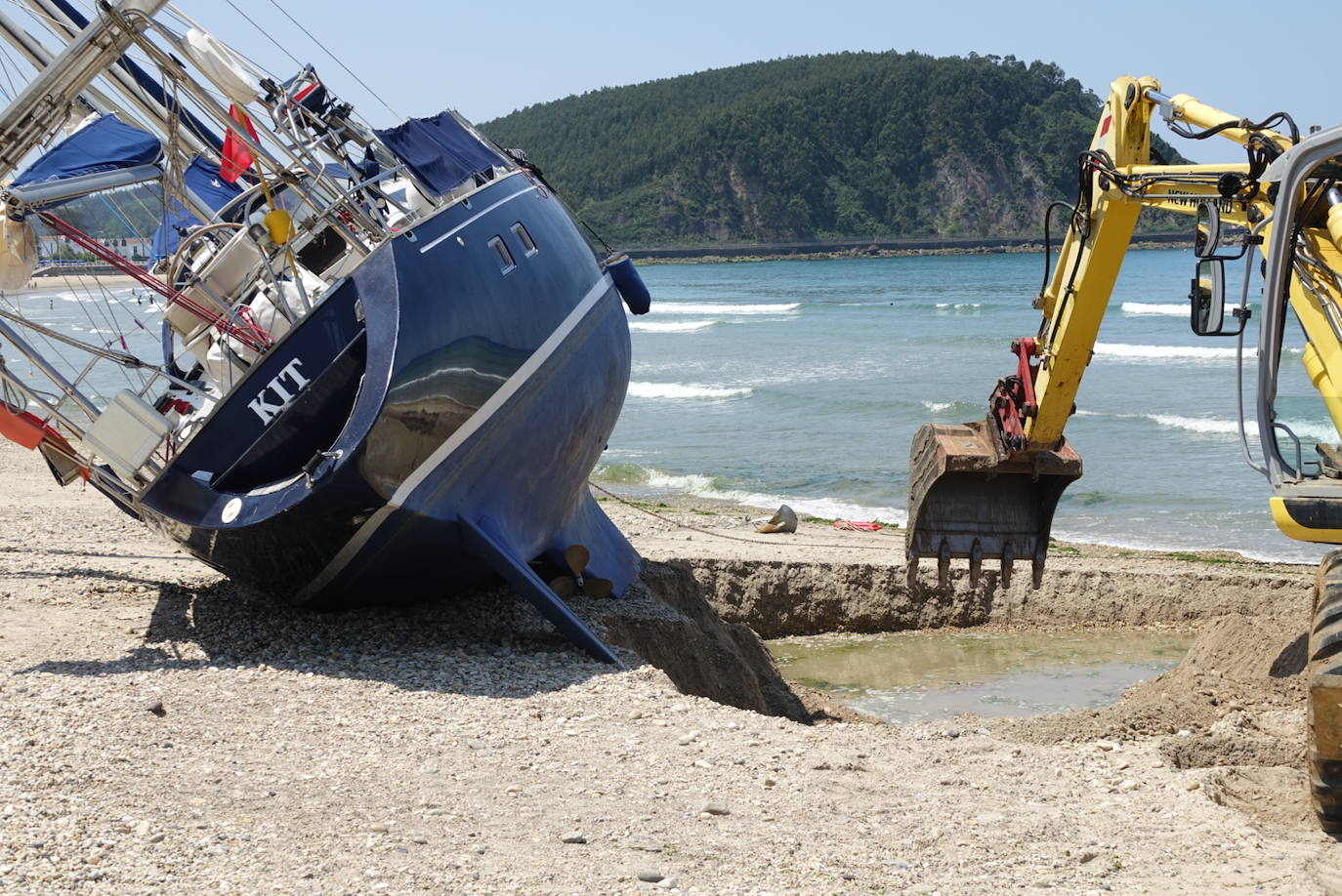 Una excavadora abre un canal en la playa de Santa Marina para intentar facilitar el posterior arrastre en pleamar del barco varado