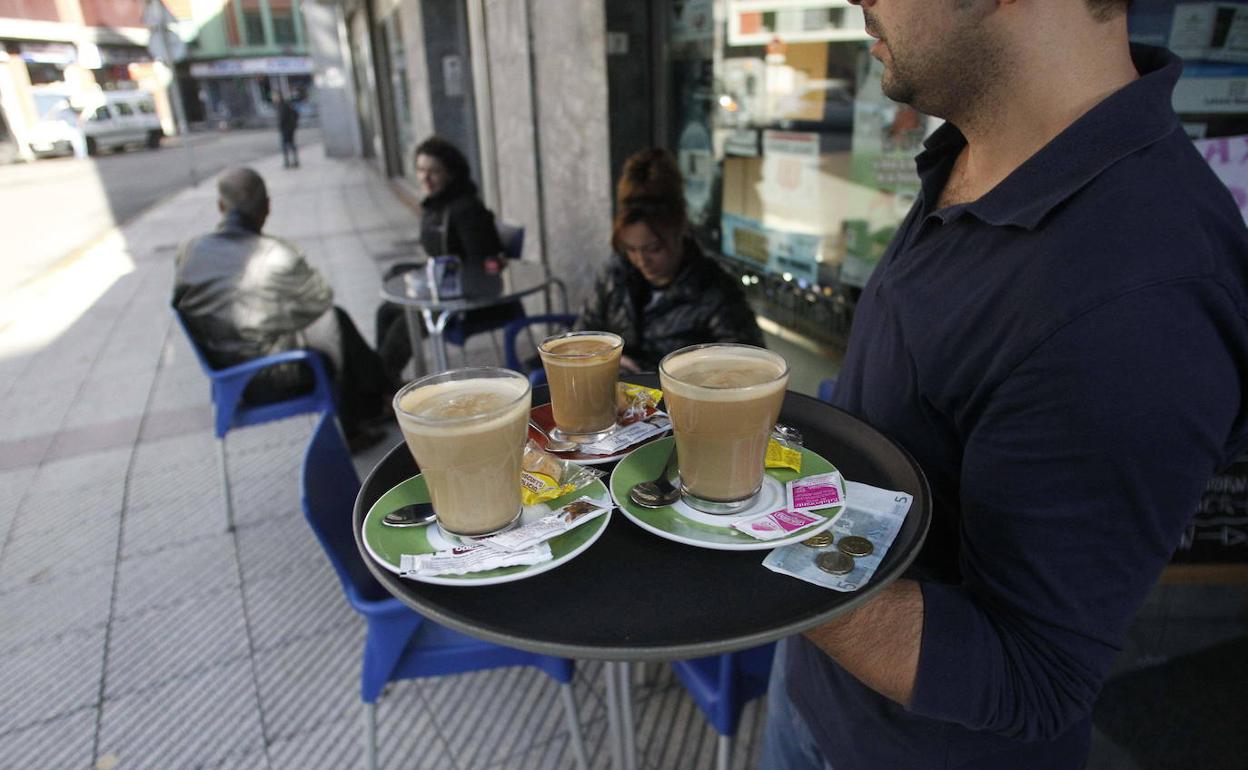 Un camarero sirve cafés en una terraza. 