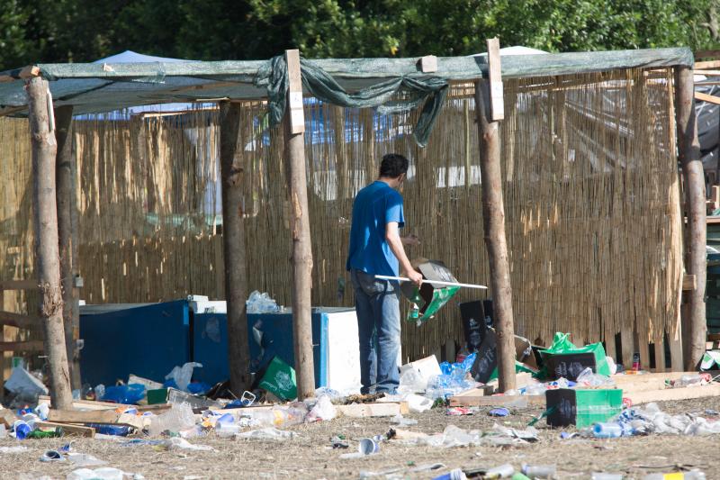 La multitudinaria fiesta del Xiringüelu ha dejado toneladas de basura en el prau Salcéu. Botellas, vasos, y restos de las coloridas casetas que son seña de identidad de la celebración han quedado esparcidos por el campo a la espera de que se retiren, unas labores que ya han comenzado.