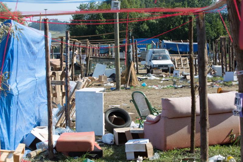 La multitudinaria fiesta del Xiringüelu ha dejado toneladas de basura en el prau Salcéu. Botellas, vasos, y restos de las coloridas casetas que son seña de identidad de la celebración han quedado esparcidos por el campo a la espera de que se retiren, unas labores que ya han comenzado.