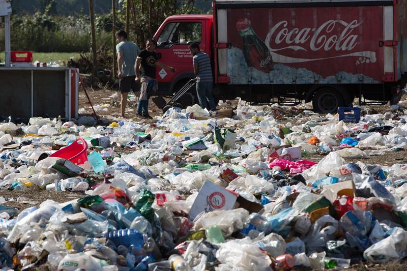 La multitudinaria fiesta del Xiringüelu ha dejado toneladas de basura en el prau Salcéu. Botellas, vasos, y restos de las coloridas casetas que son seña de identidad de la celebración han quedado esparcidos por el campo a la espera de que se retiren, unas labores que ya han comenzado.