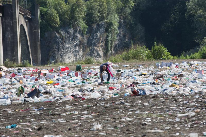 La multitudinaria fiesta del Xiringüelu ha dejado toneladas de basura en el prau Salcéu. Botellas, vasos, y restos de las coloridas casetas que son seña de identidad de la celebración han quedado esparcidos por el campo a la espera de que se retiren, unas labores que ya han comenzado.