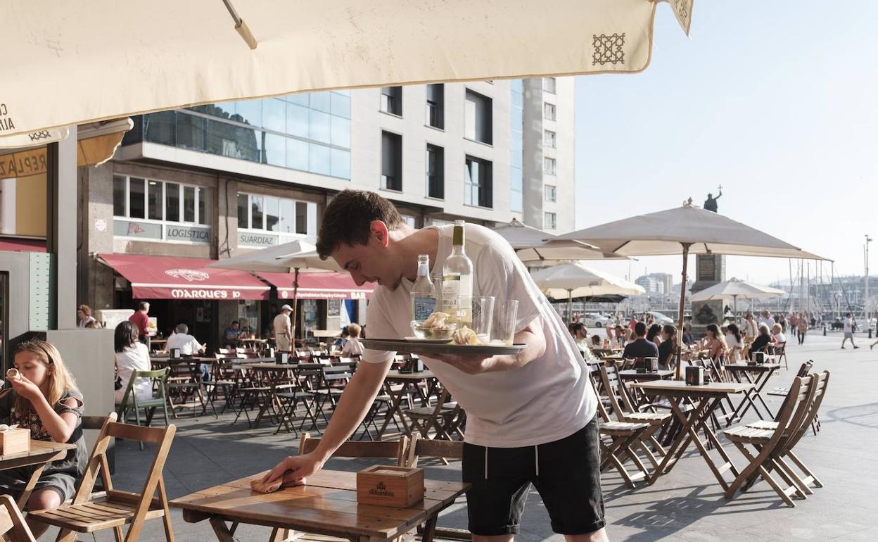 Un camarero recoge una mesa en la Plaza del Marqués. 