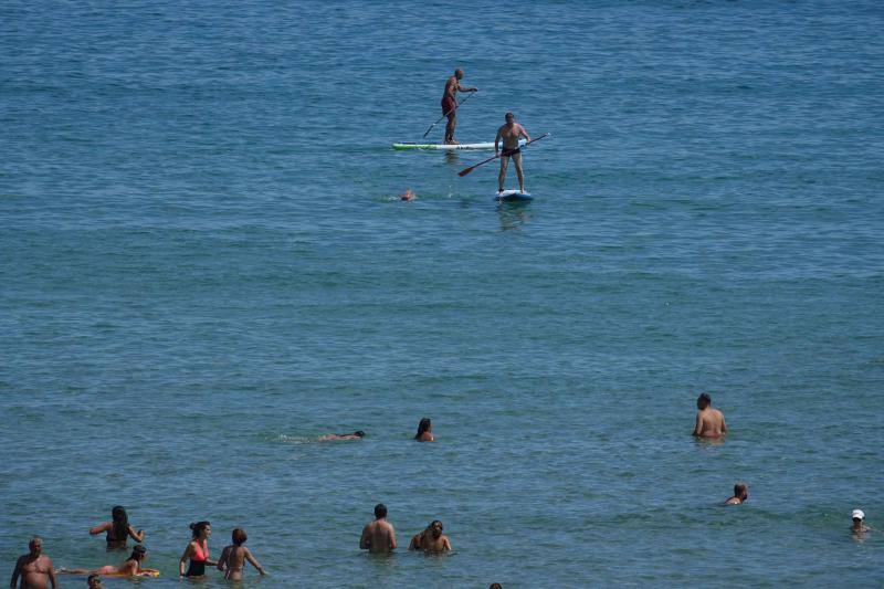 Un baño en la playa para combatir el calor en Gijón