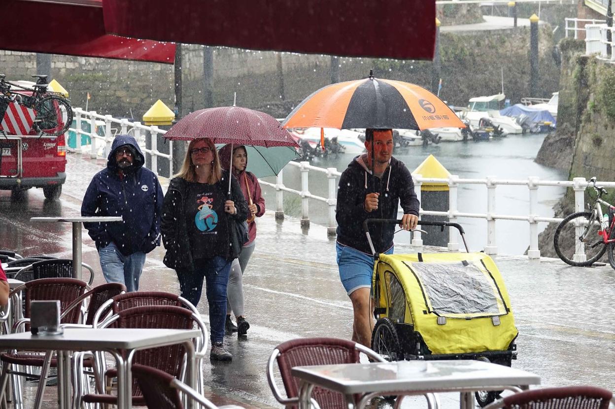 Unos turistas pasean por Llanes a pesar de la insistente lluvia. 