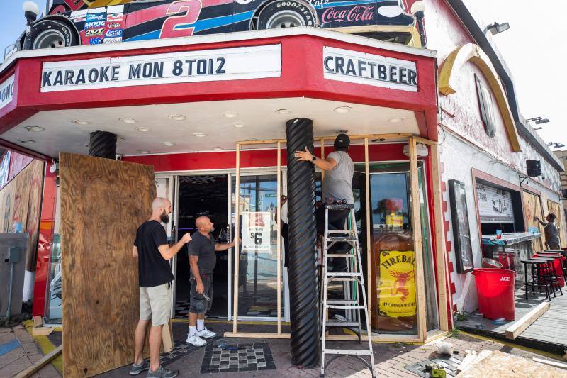 Trabajadores instalan madera frente a puertas de vidrio este domingo dentro de los preparativos para el impacto del huracán Dorian en Daytona Beach, Florida.