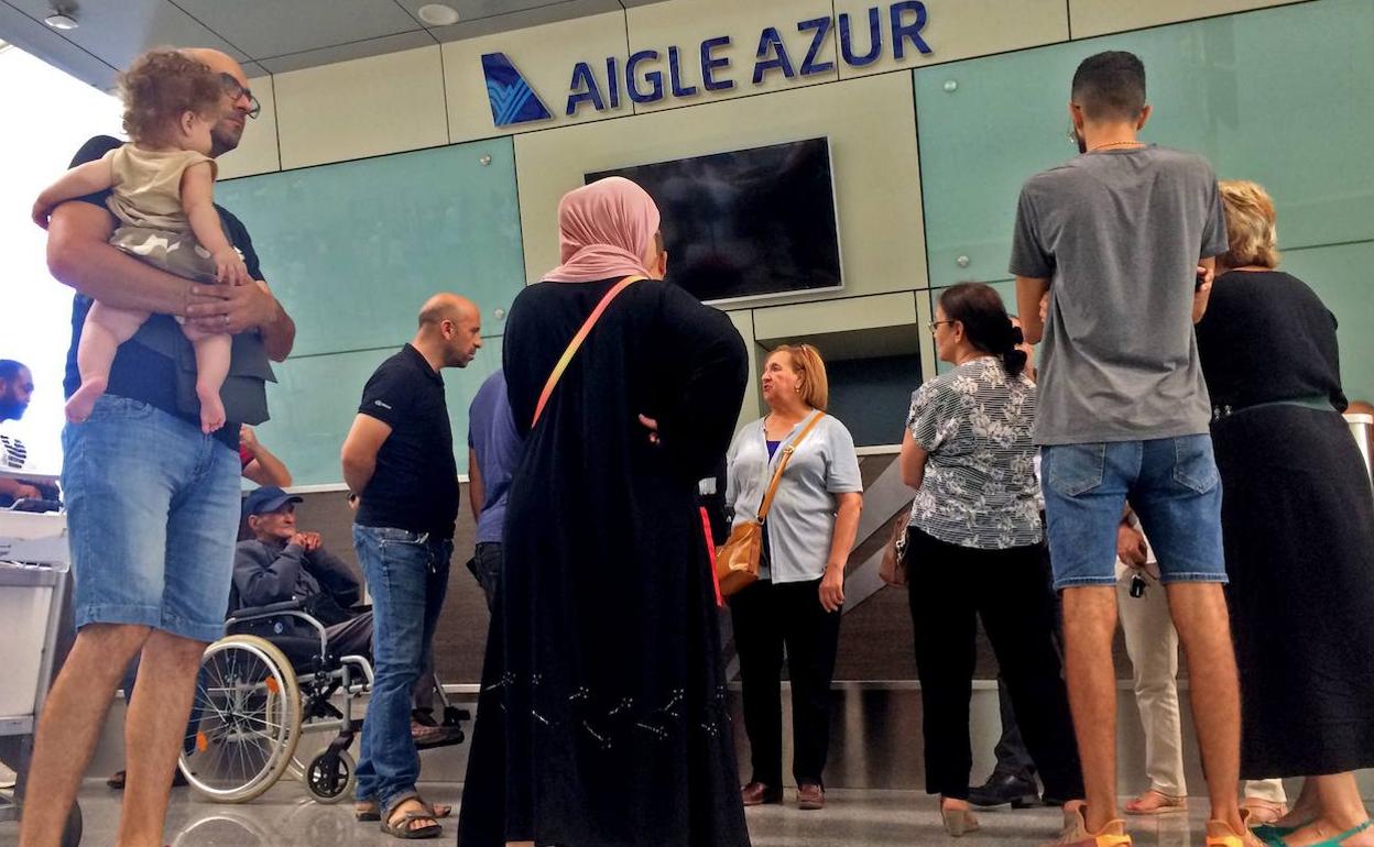 Varias personas esperan ante un mostrador de Aigle Azur. 