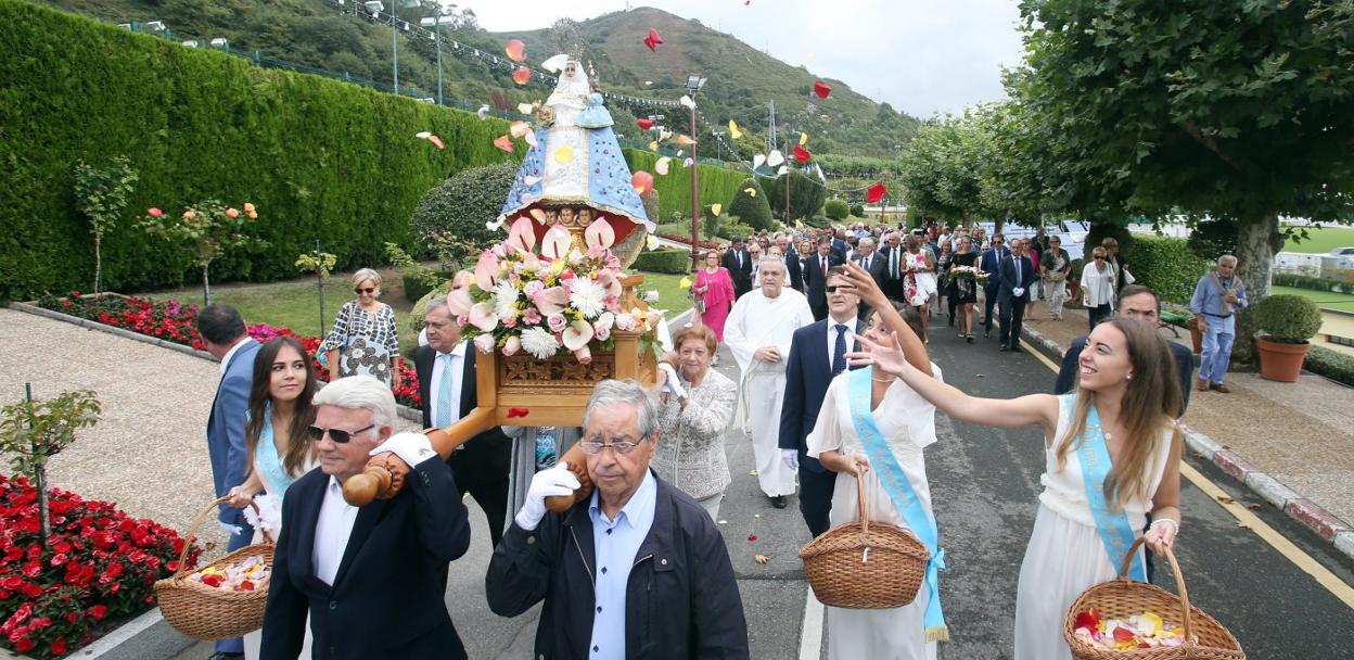 La imagen de La Santina durante la procesión, llevada a hombros por varios socios y con las damas del Centro Asturiano lanzando pétalos de rosa sobre ella. 