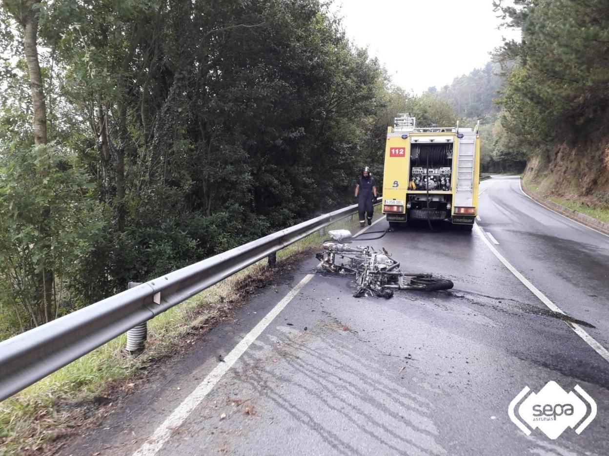 Los bomberos extinguen el incendio en la moto en Vegadeo. 