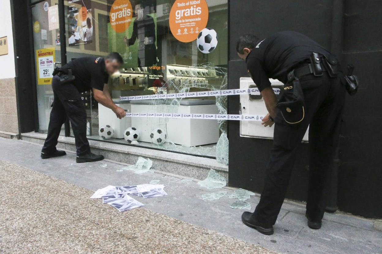 Dos agentes de la Policía Nacional precintando ayer el escaparate de la tienda. 