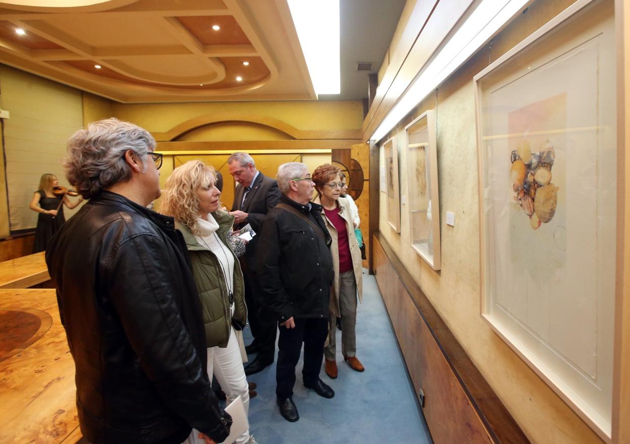 Varios asistentes, contemplando algunos de los cuadros de Fernando Fueyo en el salón de plenos de la Cámara de Comercio. 