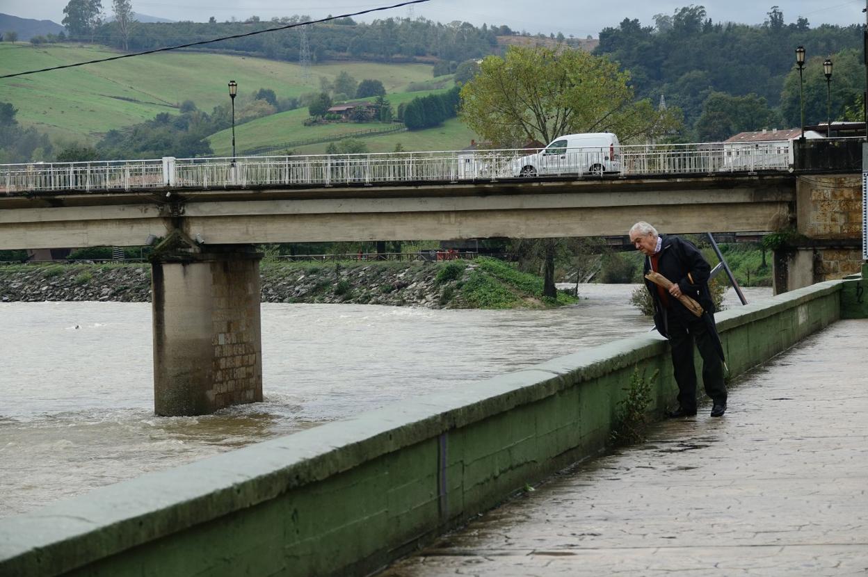 Un vecino observa el río Sella en Arriondas. 