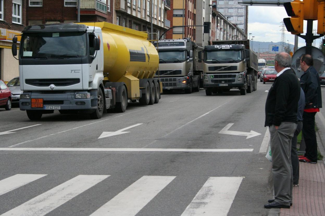 Tránsito de camiones por la avenida del Príncipe de Asturias, atravesando La Calzada hacia El Musel. 