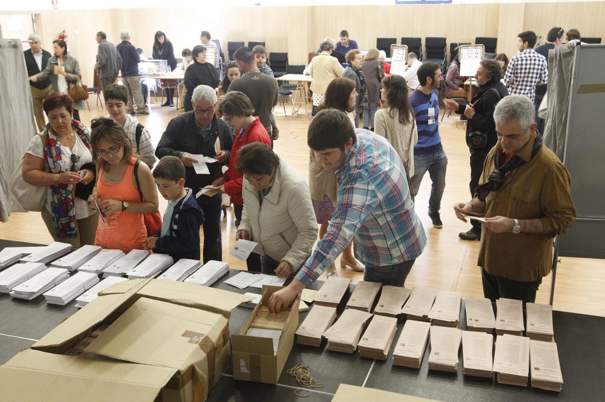 Votantes escogiendo sus papeletas en la urnas instaladas en un colegio electoral de Gijón. 