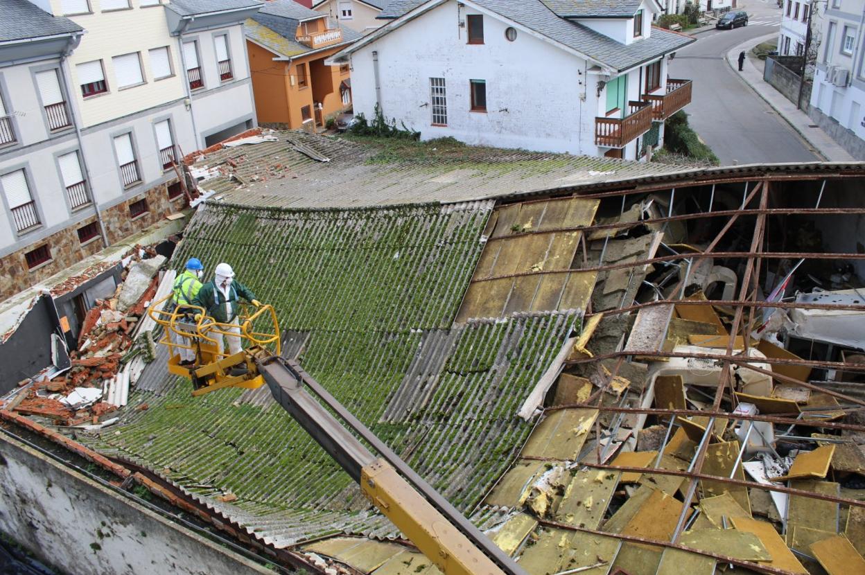 Operarios de una empresa especializada trabajan en retirar las placas de uralita del tejado, que contienen amianto. 