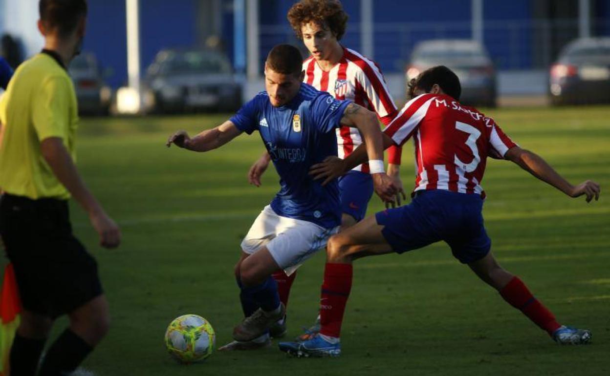 Un jugador del Vetusta trata de esquivar a dos colchoneros. 