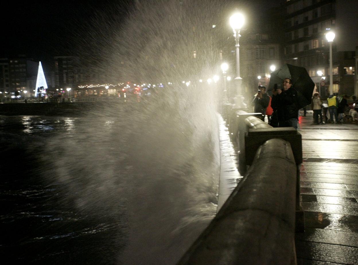 Varias personas, haciendo fotos a las olas que rompían en el paseo de El Muro. 