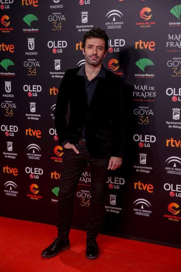 El director acertó de pleno con este look causal y elegante formado por unos pantalones en negro con acabado brillante, una camisa gris y una americana de terciopelo negra.