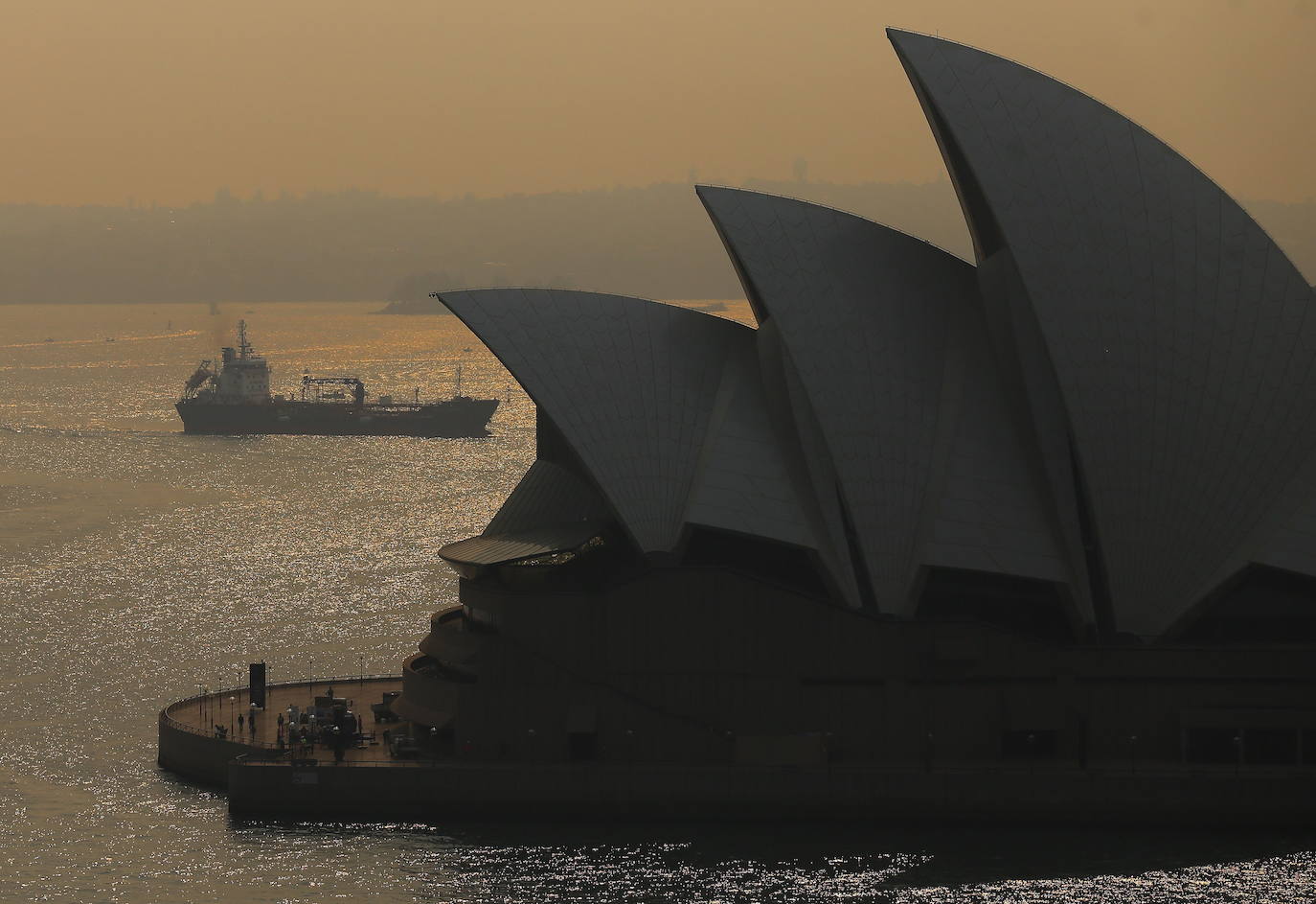 Un ferry cruza frente a la ópera de Sidney donde el humo de los fuegos provenientes de Gales del Sur han cubierto el cielo