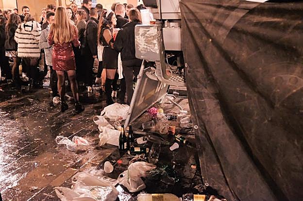 Los jóvenes, aún de fiesta, junto a montones de residuos. 