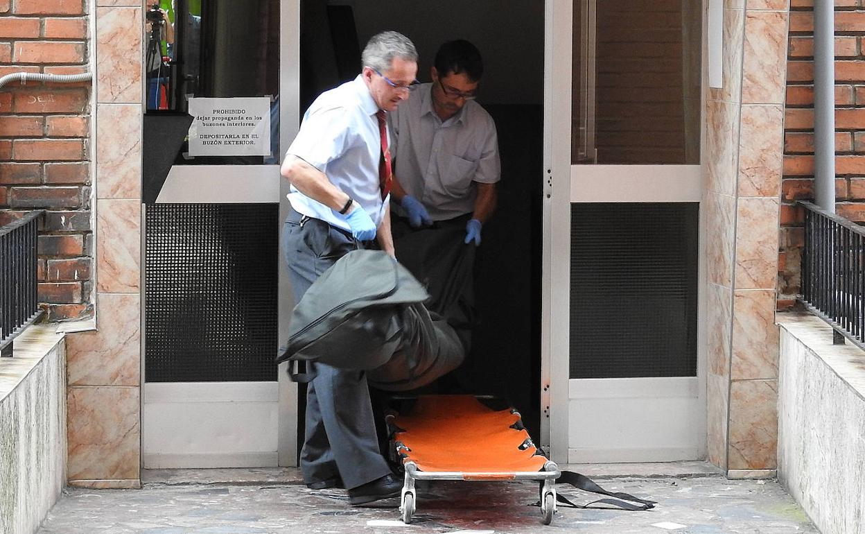 Dos operarios de una funeraria sacan el cadáver de una mujer, víctima de la violencia de género.