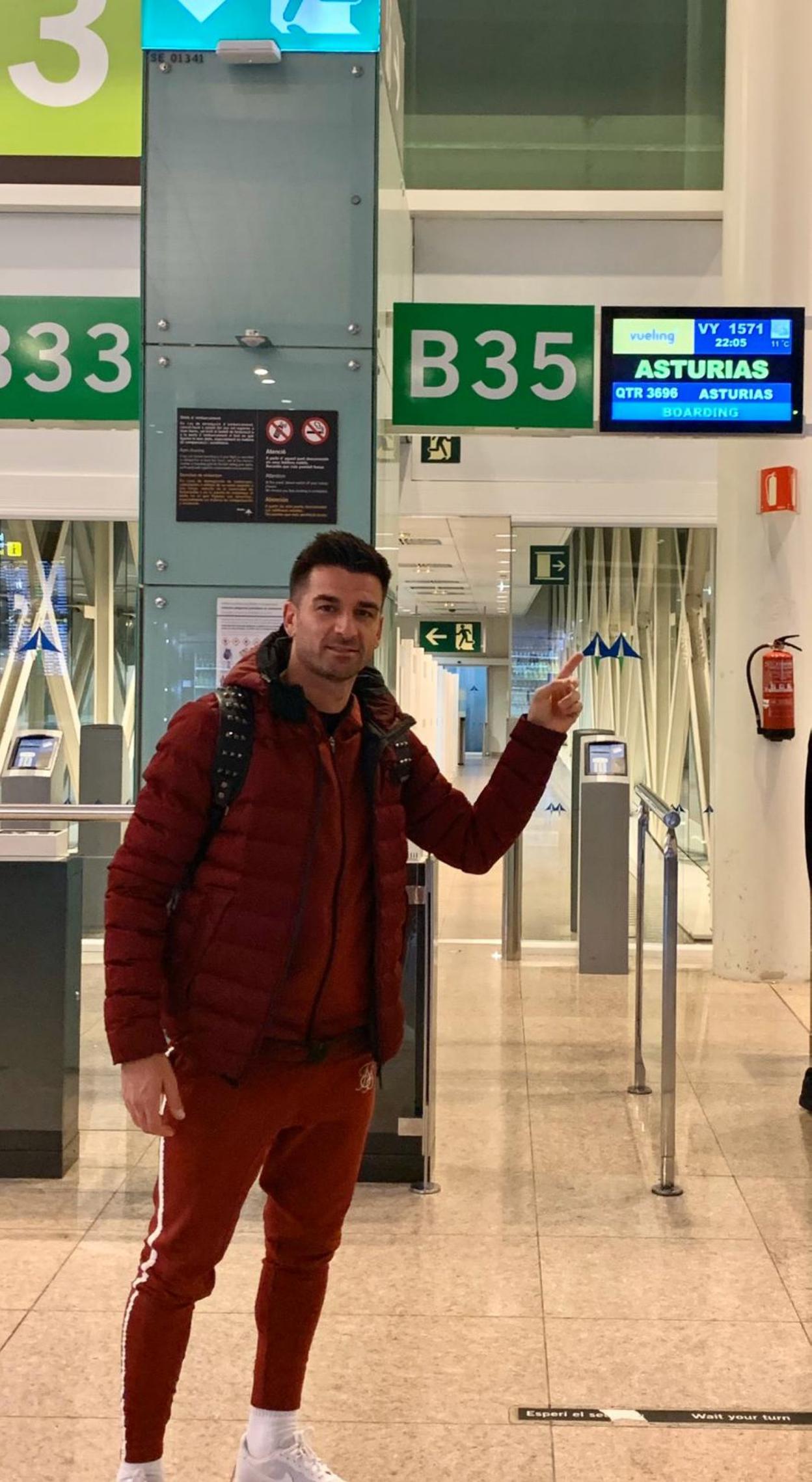 Natalio señala el cartel de Asturias antes de tomar su avión desde Barcelona ayer por la tarde.